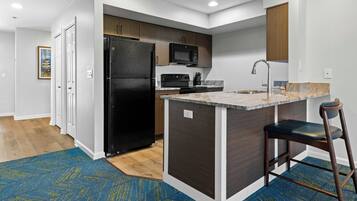A modern kitchen with a black refrigerator, a microwave, and a sink with a faucet.
