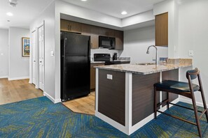 A modern kitchen with a black refrigerator, a microwave, and a sink with a faucet. - WorldMark Wolf Creek (Eden)