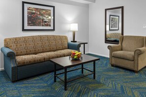 A hotel room with a patterned sofa, a small table with fruit, a lamp, and a chair. - WorldMark Wolf Creek (Eden)