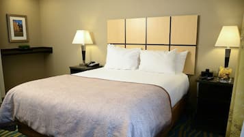 A hotel room with a large bed, two bedside tables with lamps, a nightstand with a phone, and a framed picture on the wall.