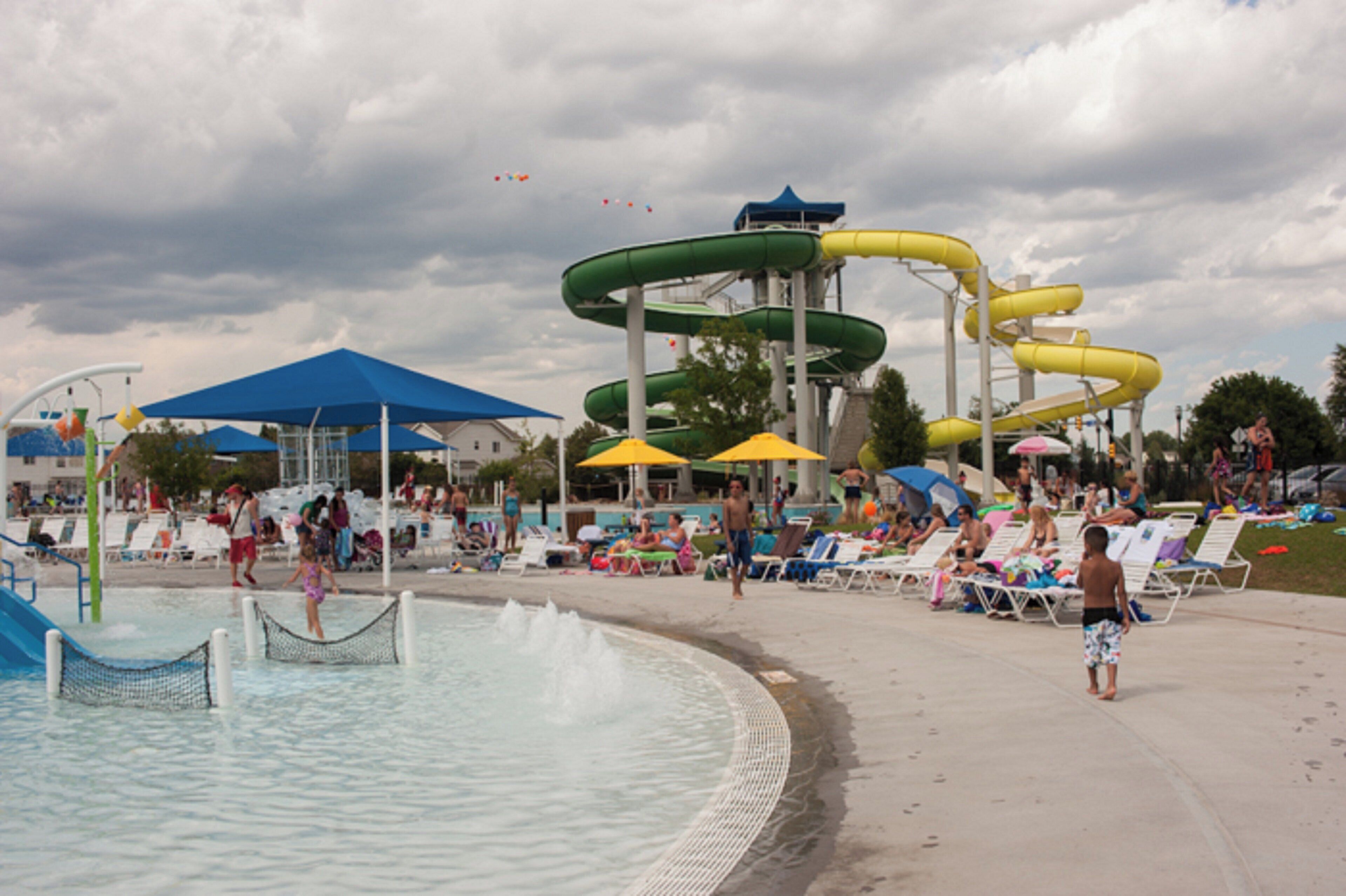 Un parque acuático con toboganes y una piscina con sillones de descanso y sombrillas.