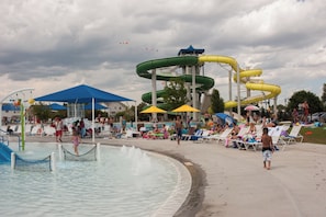Een waterpark met meerdere glijbanen en een zwembadgedeelte met ligbedden en parasols.