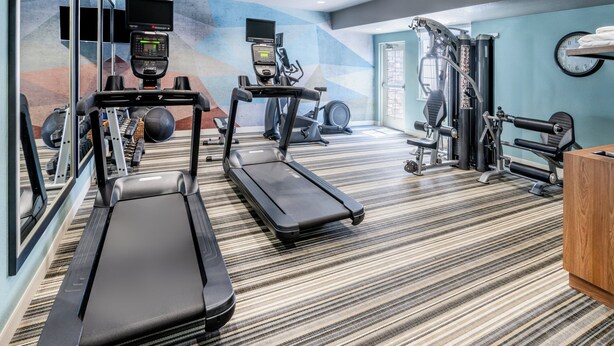 Une salle de sport équipée de tapis de course, de vélos elliptiques et de matériel de musculation.