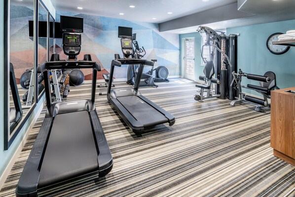 Een sportschool met loopbanden, elliptische trainers en gewichten.