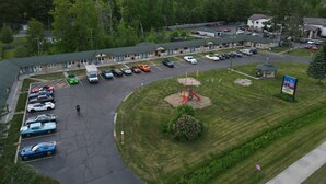 A motel with a parking lot, a playground, and a sign for The Crow's Nest Inn. - Crows Nest Inn Tawas (Tawas City)
