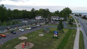 A motel with a parking lot, a playground, and a sign for The Crow's Nest Inn. - Crows Nest Inn Tawas (Tawas City)
