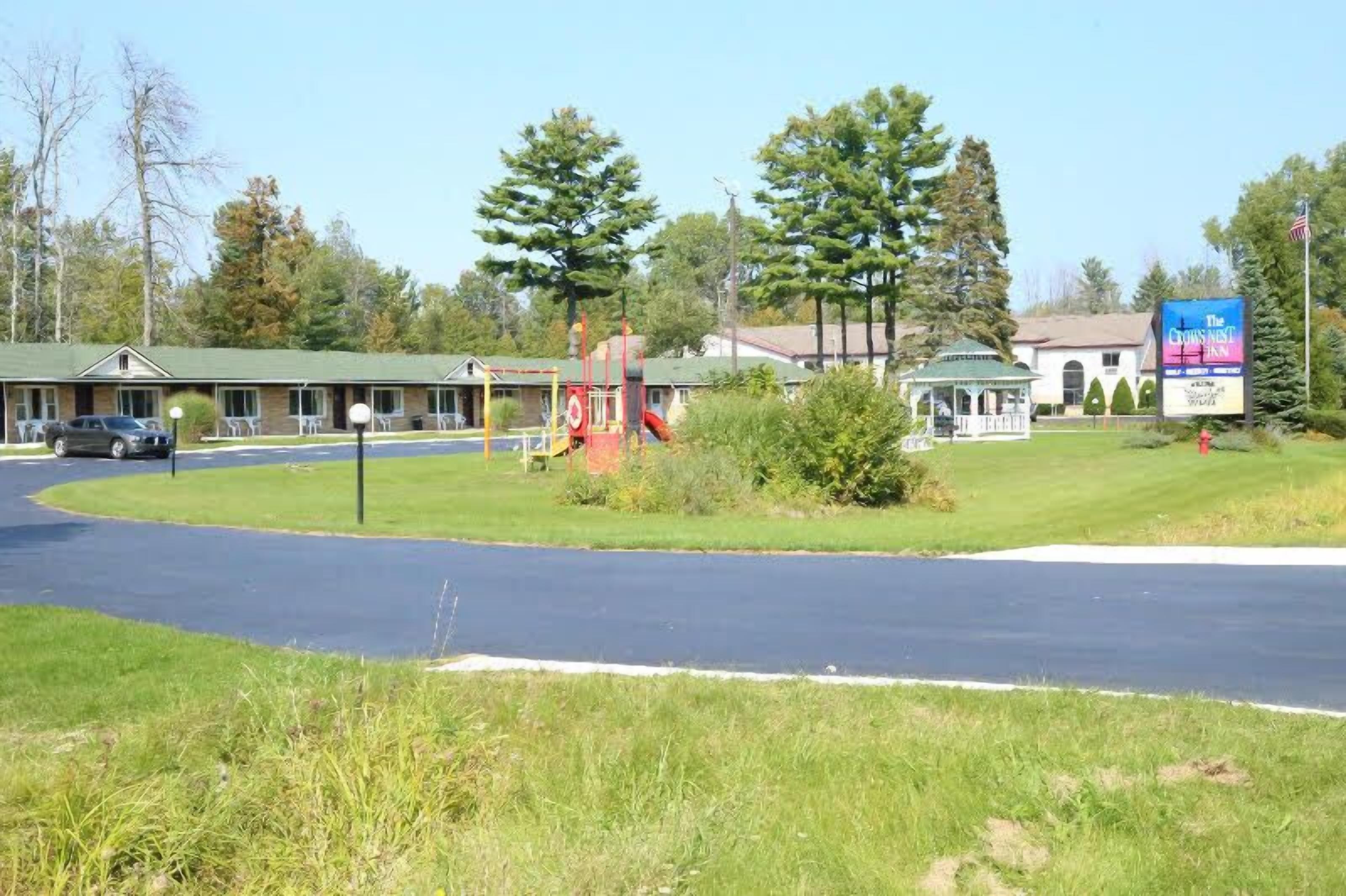 Un motel con techo verde, un parque infantil y un letrero que dice The Crow's Nest Inn.