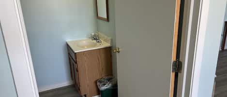 A small bathroom with a wooden vanity, a sink, and a mirror.