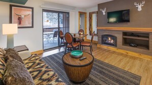 Ein Wohnzimmer mit Kamin, Deckenventilator, Wand-Fernseher und Essbereich mit Stühlen und Tisch.