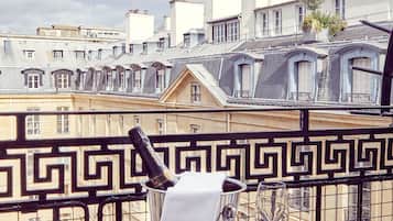 Un balcon avec une table dressée pour deux personnes, agrémentée d’une bouteille de champagne et de deux verres.