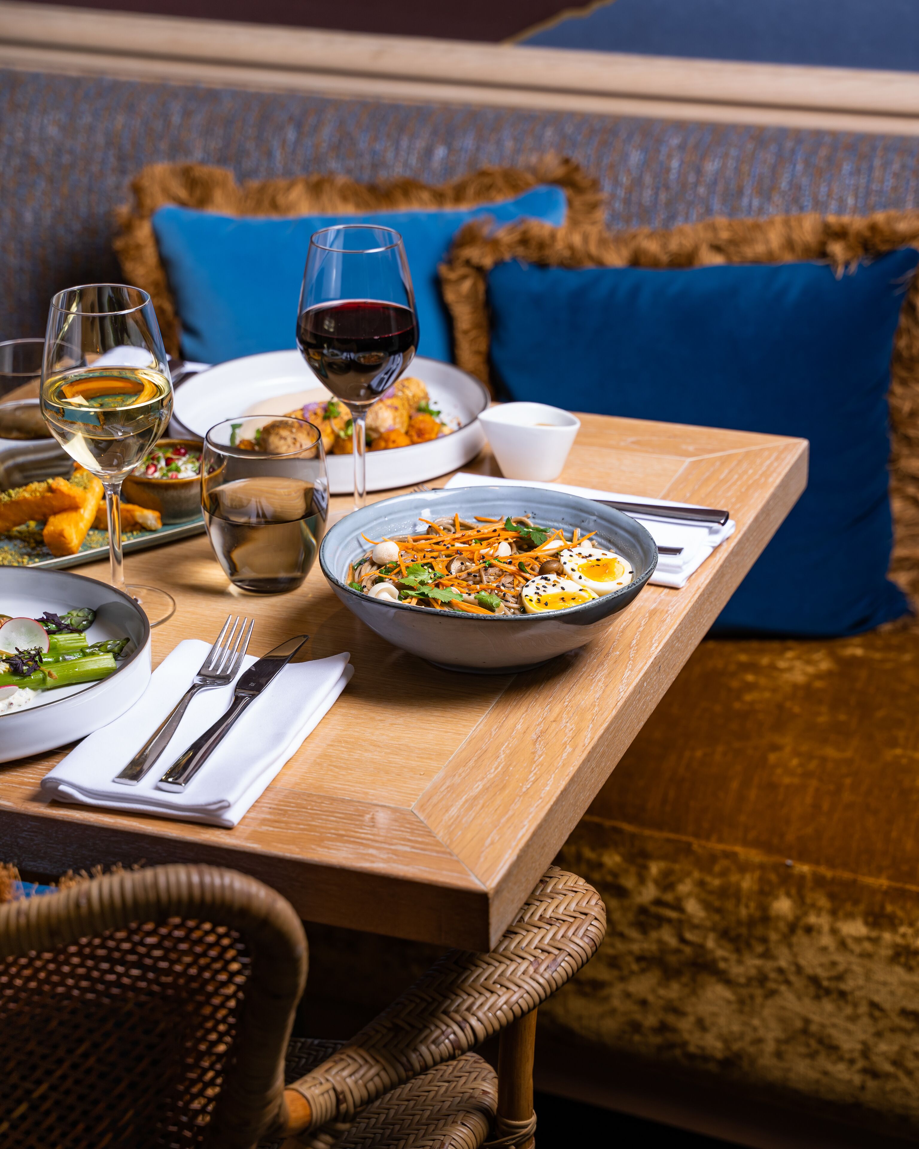Una mesa de comedor con platos de comida, copas de vino y cubiertos.