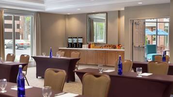 A conference room with tables and chairs, a coffee station, and a view of the outside.