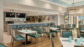 A restaurant with a bar area, teal chairs, and a nautical-themed wall.