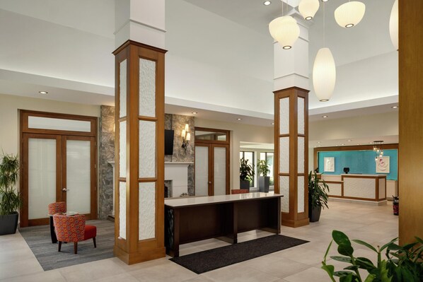 A spacious lobby with a reception desk, seating area, and decorative lighting. - Hilton Garden Inn Stony Brook (Stony Brook)