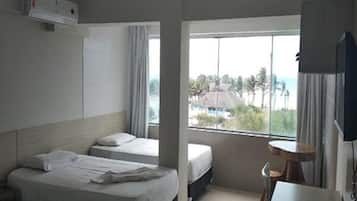 Habitación de hotel con dos camas, una mesita, una silla y un televisor.