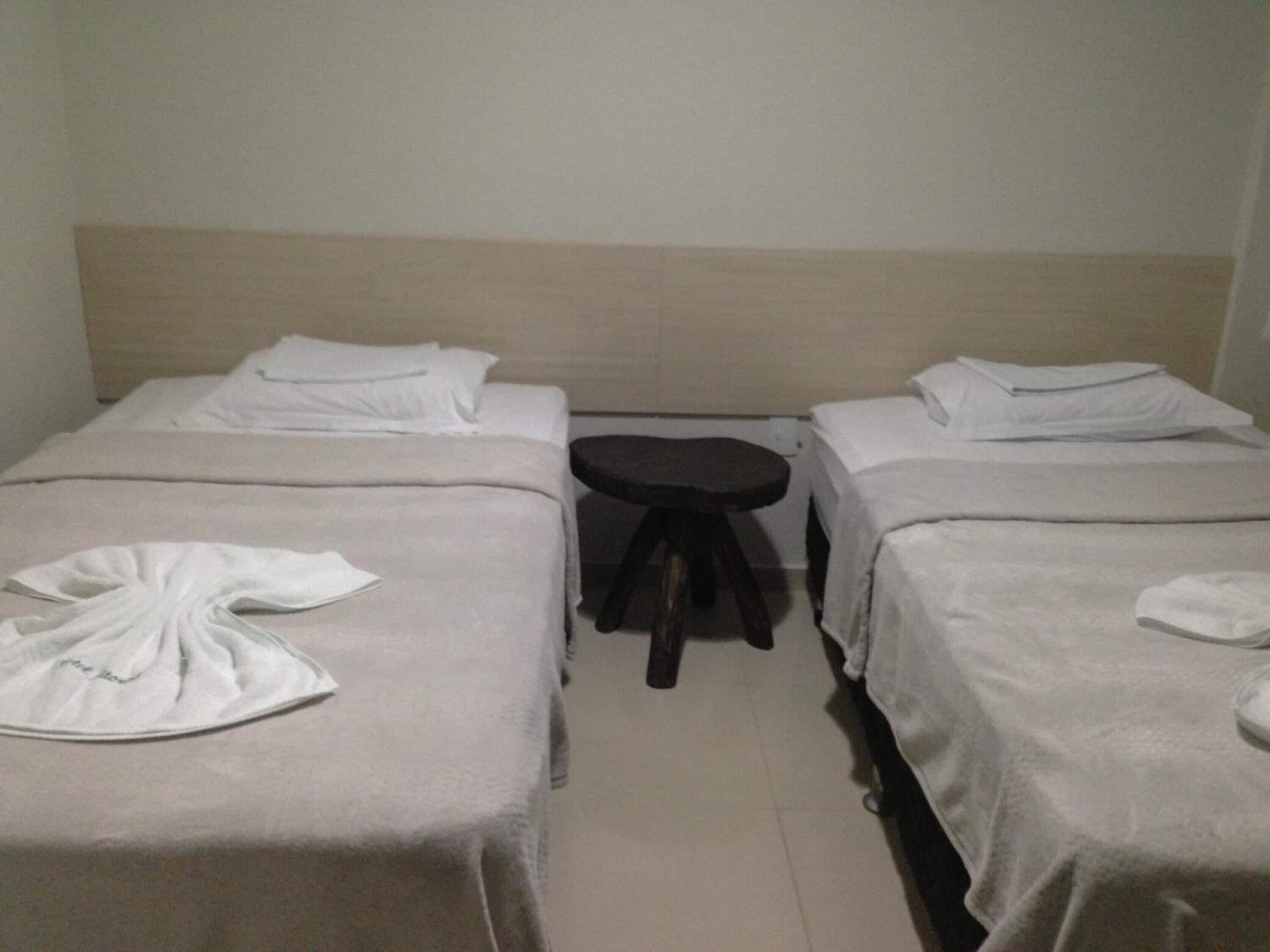 Ein Hotelzimmer mit zwei Betten, jedes mit einem ordentlich gefalteten weißen Handtuch.