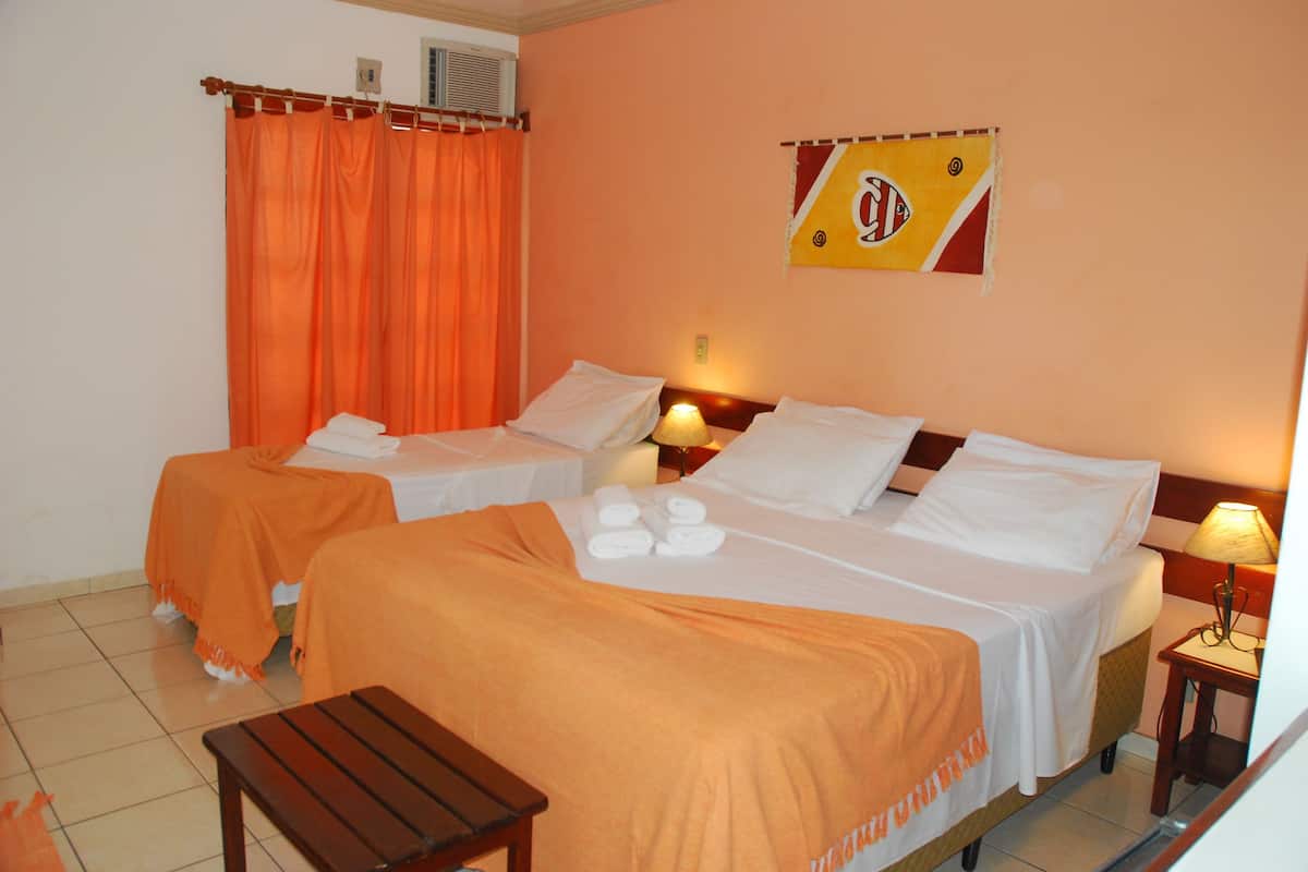 Ein Hotelzimmer mit zwei Betten, orangefarbenen Vorhängen, einer Flagge und einem kleinen Tisch.