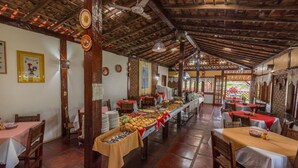 A dining area with multiple tables, a buffet with various food items, and a rustic wooden ceiling. - Pousada Aldeia Portuguesa (Santa Cruz Cabralia)