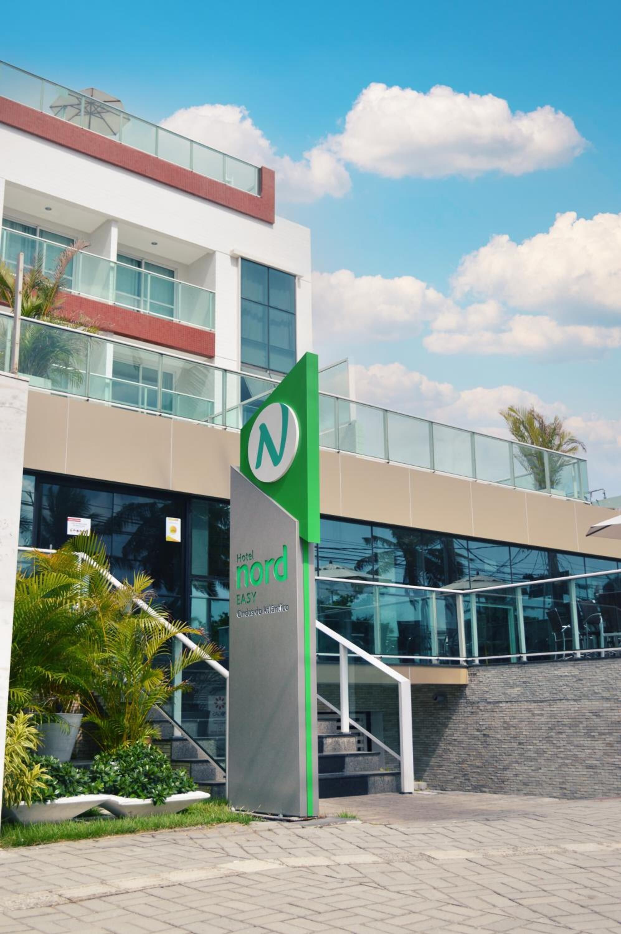 Un edificio moderno de hotel con un llamativo letrero 'Nord', ventanas de vidrio y una escalera que conduce a la entrada.
