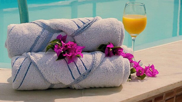 A poolside area with a glass railing, a towel, and a glass of orange juice. - Nord Easy Ondas do Atlântico (João Pessoa)