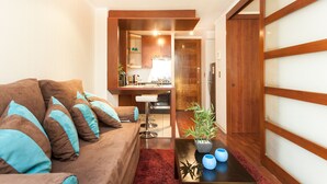 A compact living space with a sofa, a small dining area, and a kitchen in the background. - ECO PLAZA Santiago (Santiago)