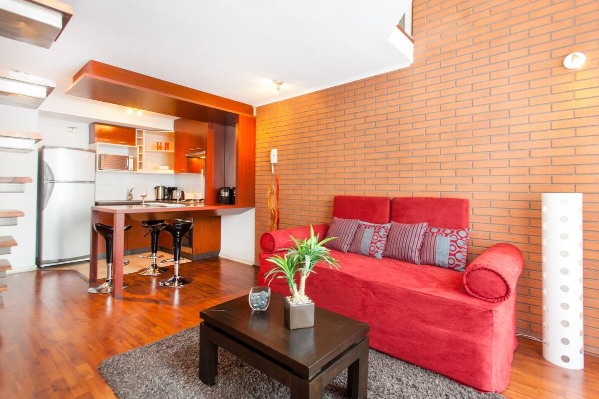 A modern living room with a red sofa, a coffee table, and a potted plant.