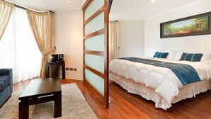 A bedroom with a bed, a desk, a chair, and a painting on the wall. - ECO PLAZA Santiago (Santiago)