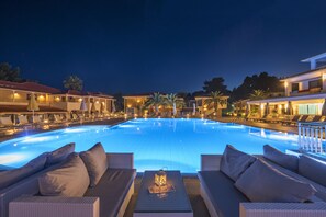 Una piscina al aire libre, sombrillas, sillones reclinables de piscina