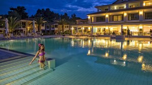 Una piscina al aire libre, sombrillas, sillones reclinables de piscina