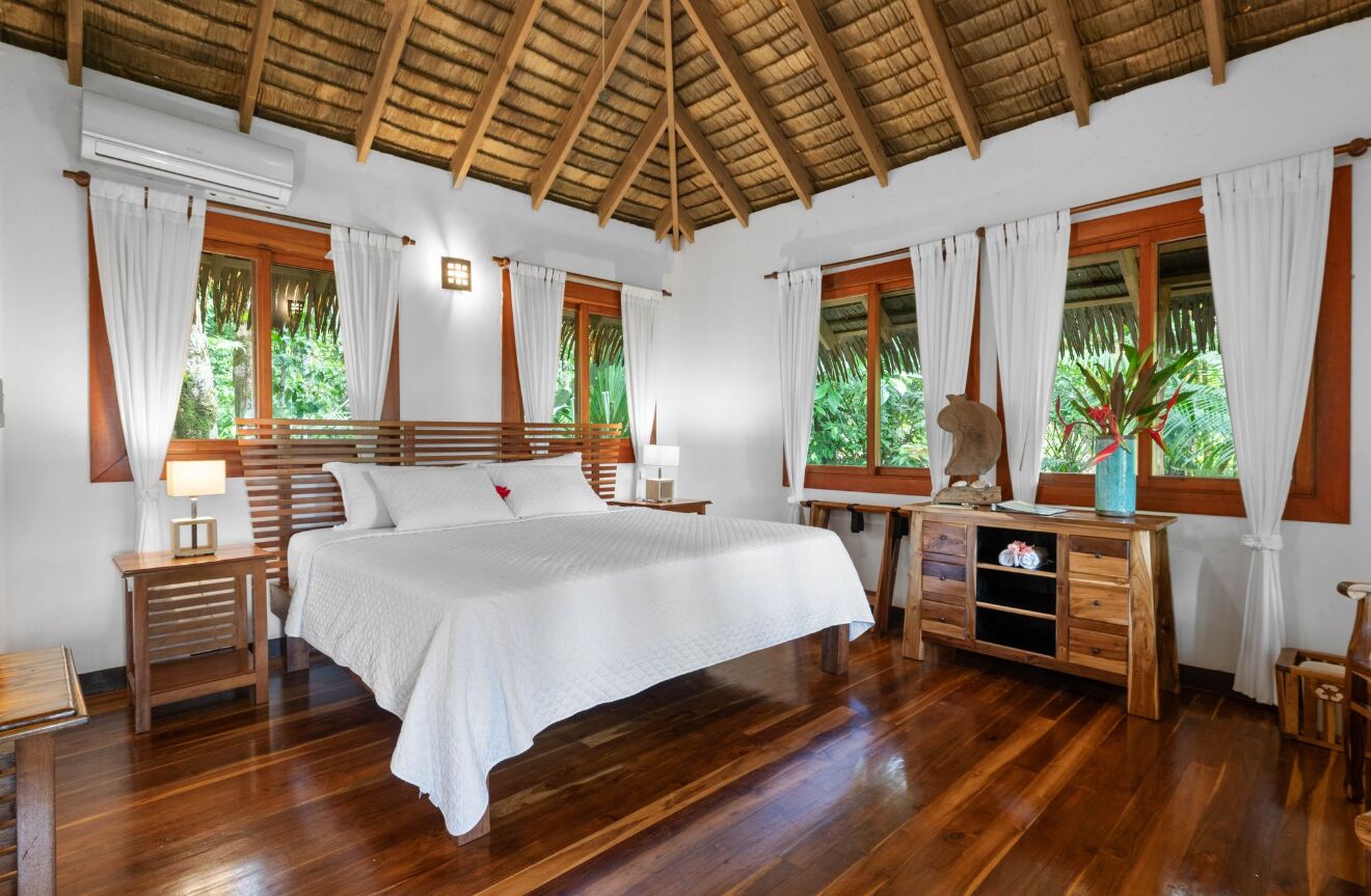 A spacious bedroom with a large bed, wooden headboard, and a wooden dresser.
