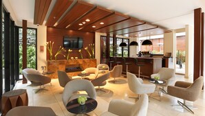 A modern interior with a bar area, seating, and a TV mounted on the wall. - Mercure Bogotá Calle 100 (Bogotá)