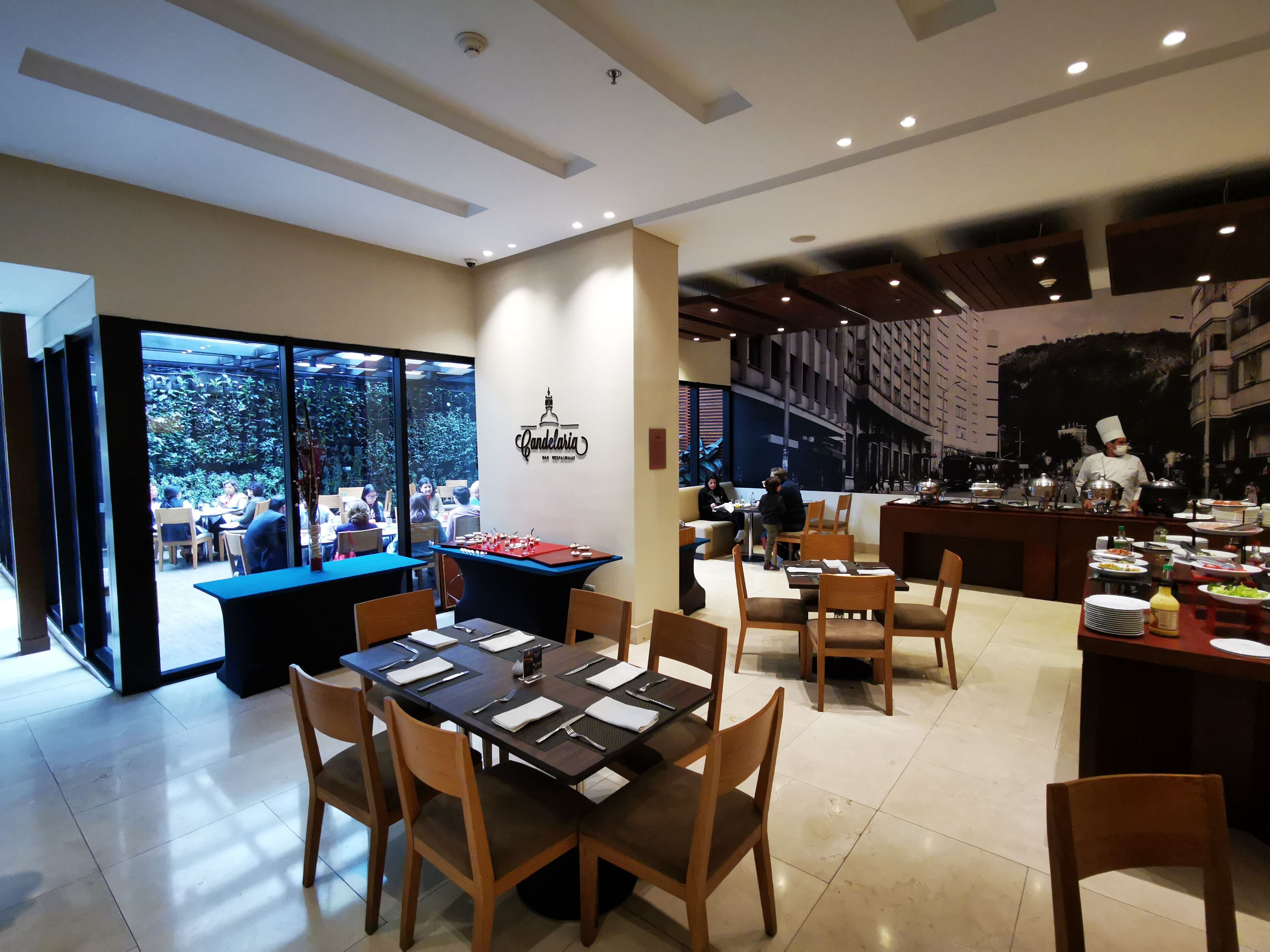 A modern dining area with tables set for guests, a pool table, and a chef at the counter.