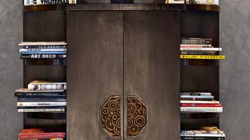 A wooden bookshelf with a decorative headpiece on top, filled with books on various topics.