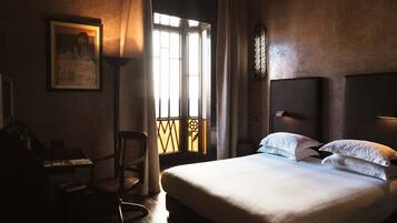 Una habitación de hotel con una cama grande, un escritorio, una silla y una ventana con cortinas.