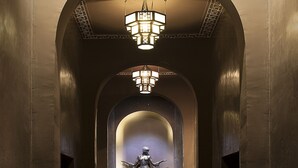 A hallway with a statue, a chandelier, and a wooden floor. - Villa Makassar (Marrakech)