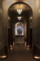 Ein Flur mit einer Statue, einem Chandelier und einem Holzboden.