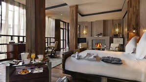 A modern hotel room with a large bed, a desk with breakfast items, a fireplace, and a view of the outdoors. - Villa Makassar (Marrakech)