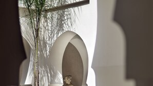 A corridor with a large white vase, a statue, and a palm tree. - Villa Makassar (Marrakech)