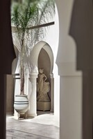 Ein Korridor mit einer großen weißen Vase, einer Statue und einer Zimmerpflanze.
