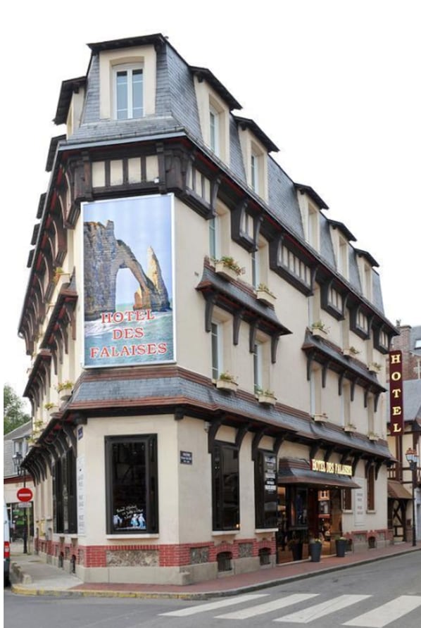Un edificio histórico con un cartel que dice "HOTEL DES FALAises" y vista al mar.