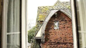 A window with a view of a brick building with a sloped roof. - Hôtel des Falaises (Etretat)