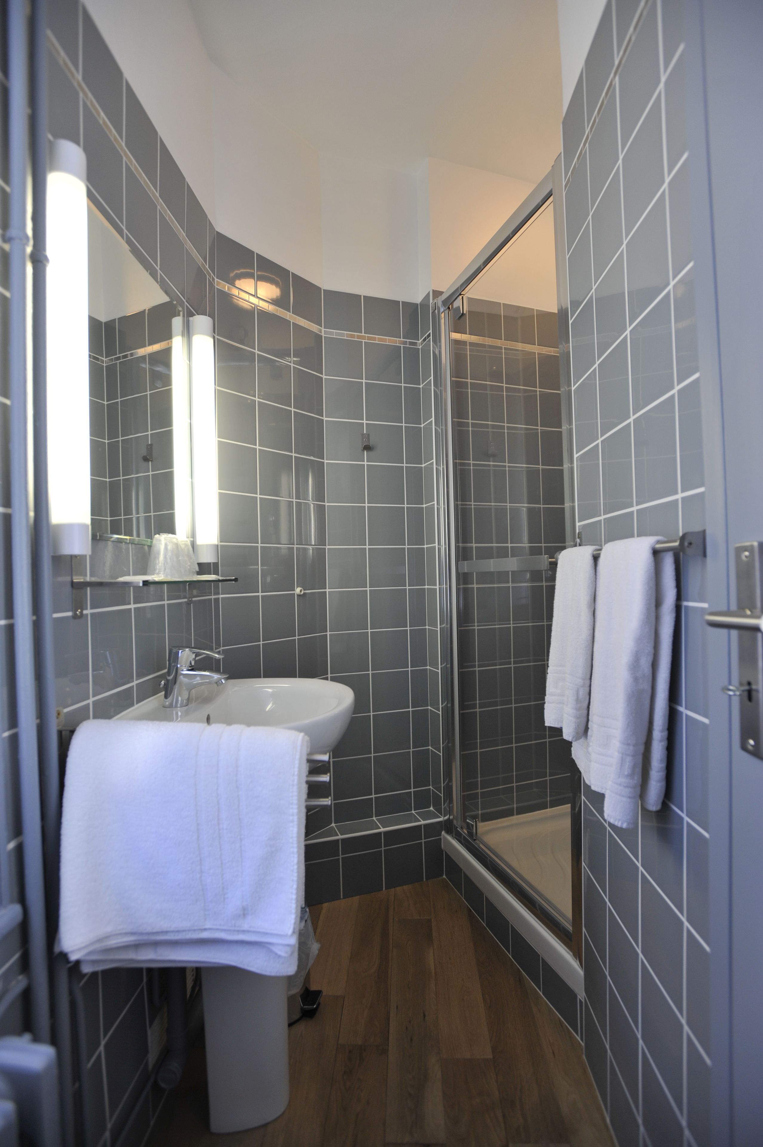 Un baño moderno con ducha de vidrio, lavamanos y espejo.