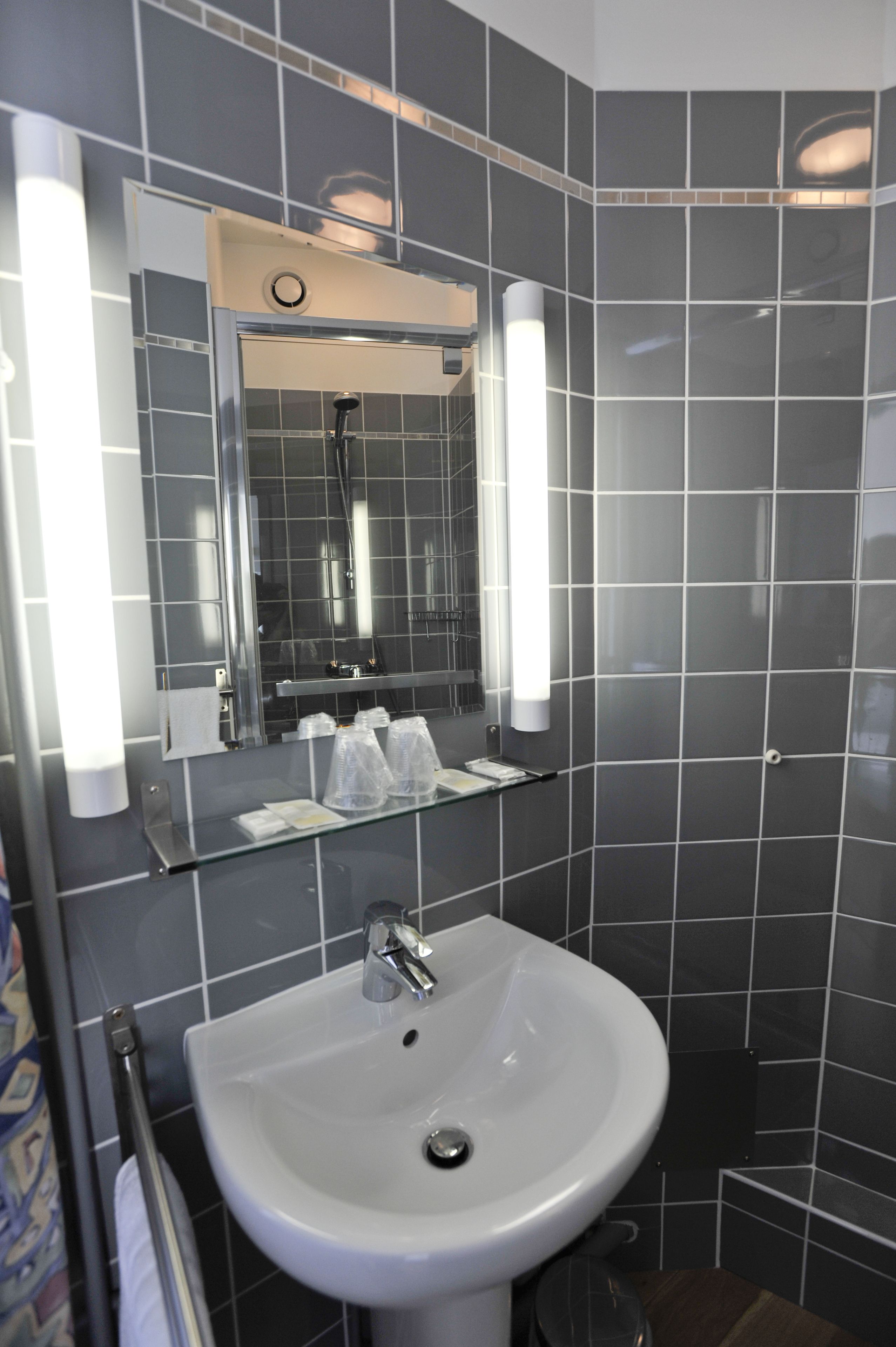 A bathroom with a white sink, a mirror, and a shower.