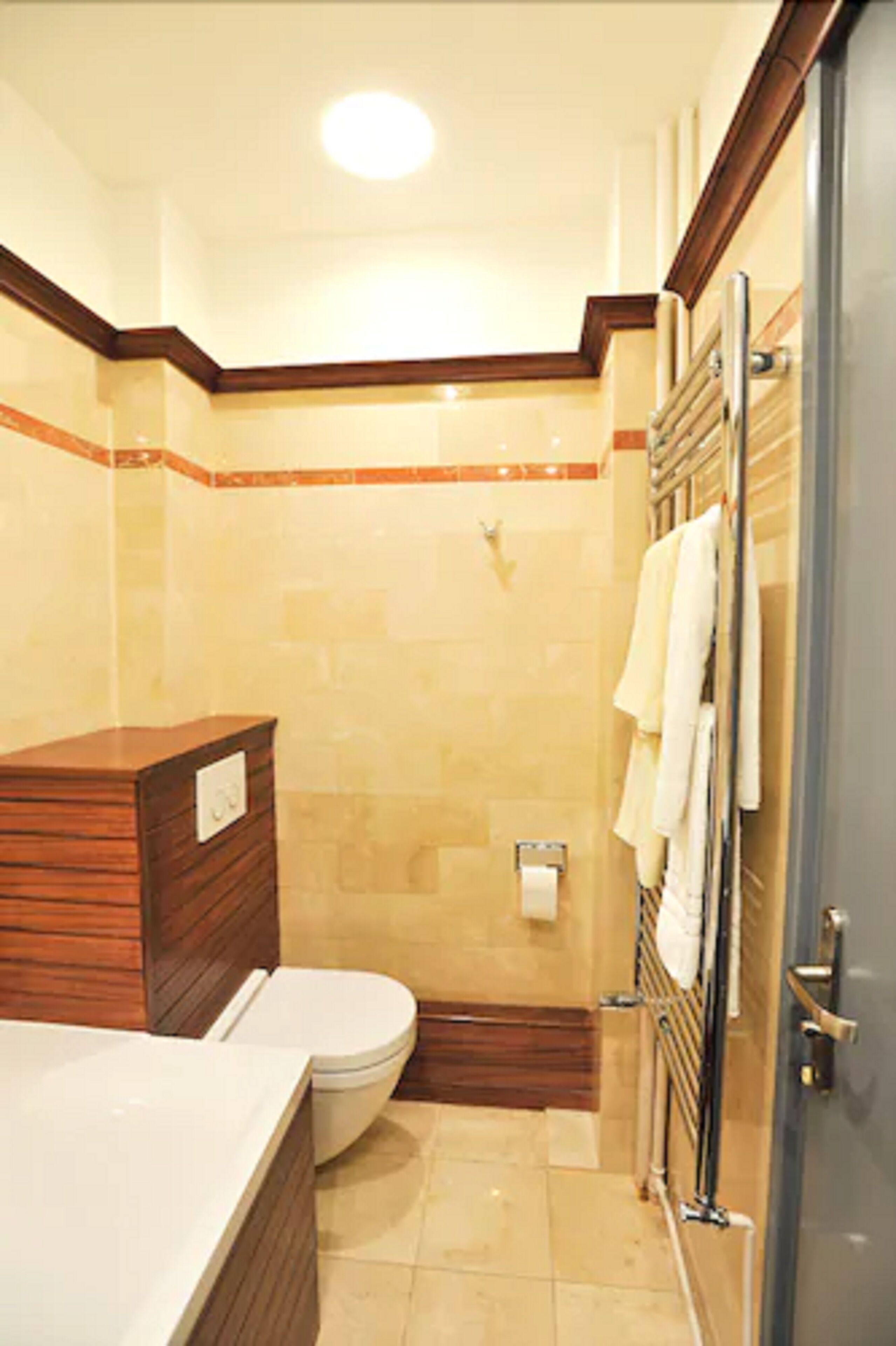 A bathroom with a wooden vanity, a toilet, a shower area, and a towel rack.