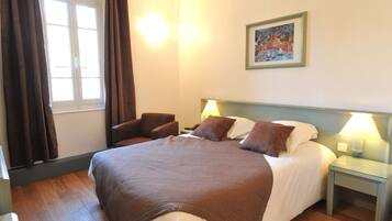 A hotel room with a large bed, two bedside lamps, a chair, a nightstand, and a window with curtains.