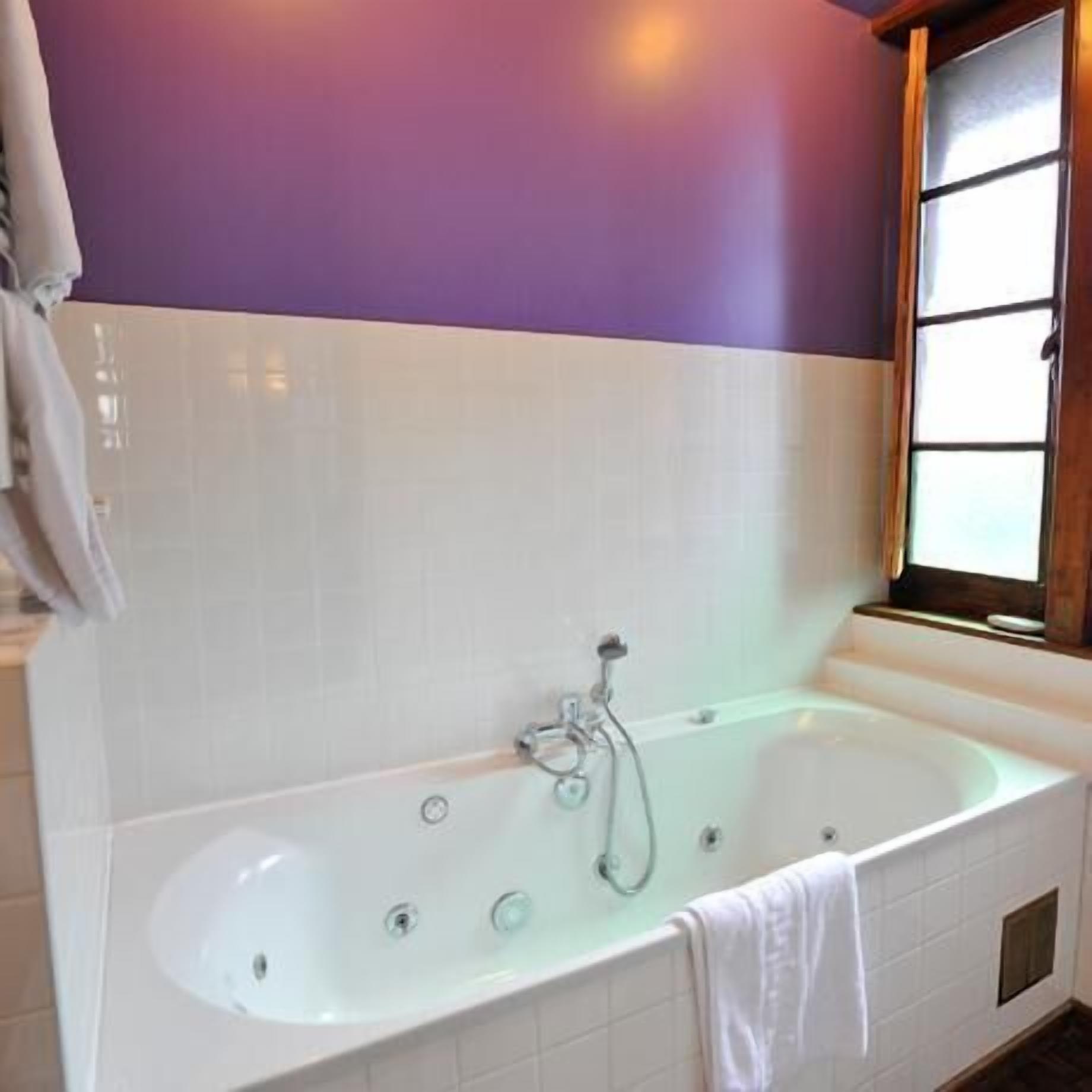 A bathroom with a freestanding bathtub, a window, and a towel hanging on the wall.