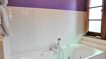 Een badkamer met een vrijstaand bad, een raam en een handdoek aan de muur.