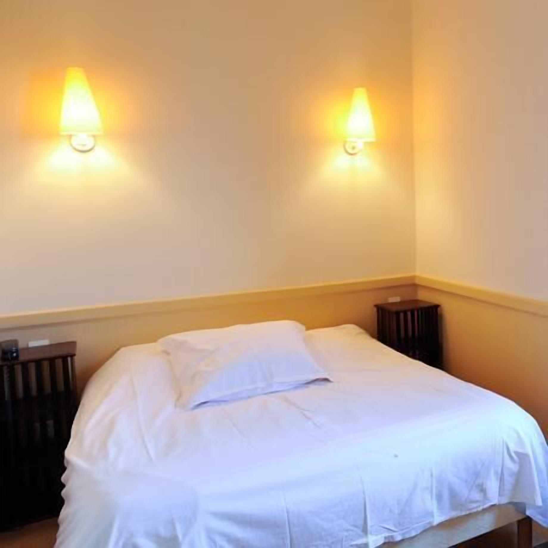 A neatly made bed with white linens in a hotel room.