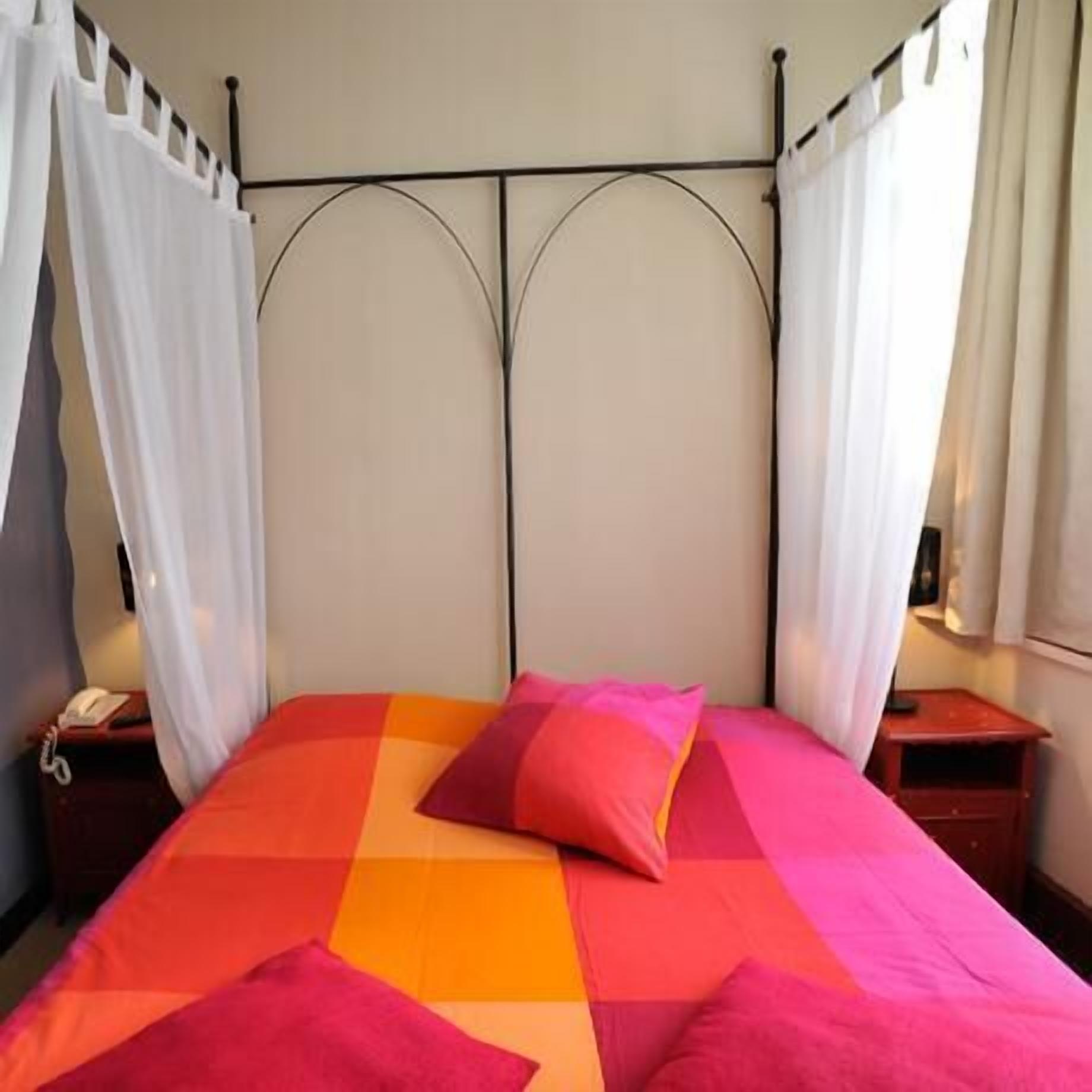 Un lit avec une couvre-lit à motifs géométriques, une table de chevet et un téléphone.