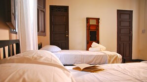 A bedroom with two single beds, a wooden wardrobe, and a mirror on the wall. - Hotel Del Parque (Santa Marta)